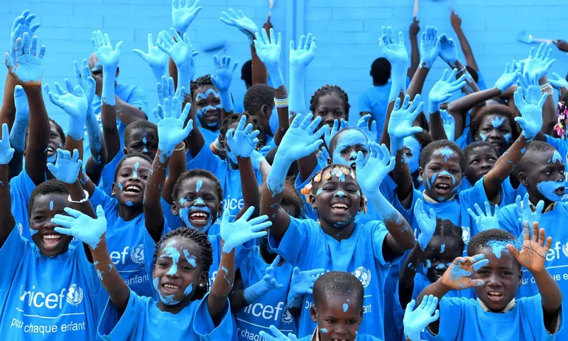 Children in UNICEF t-shirts raising their hands.